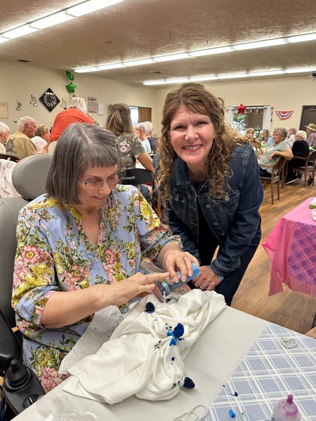 Royal Plaza resident and family member smiling and tie-dying a shirt together during an annual, community-wide Family Fun Day event hosted by Royal Plaza